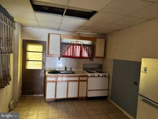 kitchen featuring sink, stainless steel fridge, a paneled ceiling, white range with gas cooktop, and decorative backsplash