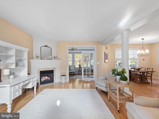 living room with light hardwood / wood-style flooring, a fireplace, a chandelier, and a healthy amount of sunlight