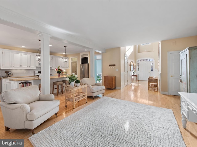 living room featuring light hardwood / wood-style flooring, decorative columns, and a chandelier