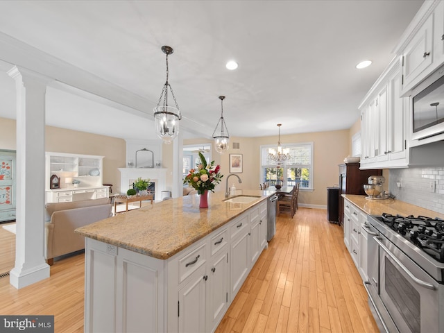 kitchen featuring sink, stainless steel appliances, white cabinets, and a center island with sink