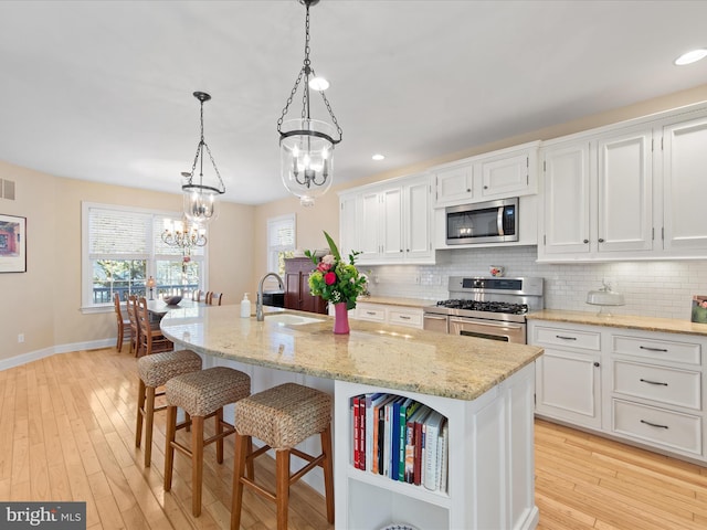 kitchen featuring appliances with stainless steel finishes, an island with sink, and white cabinets