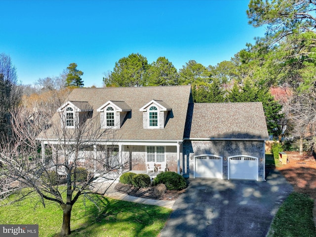 cape cod home with a porch, a garage, and a front lawn