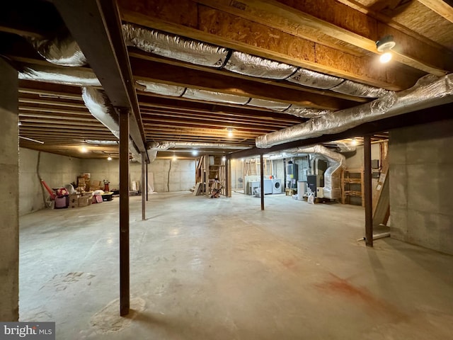 unfinished basement with heating unit, water heater, and washer and clothes dryer