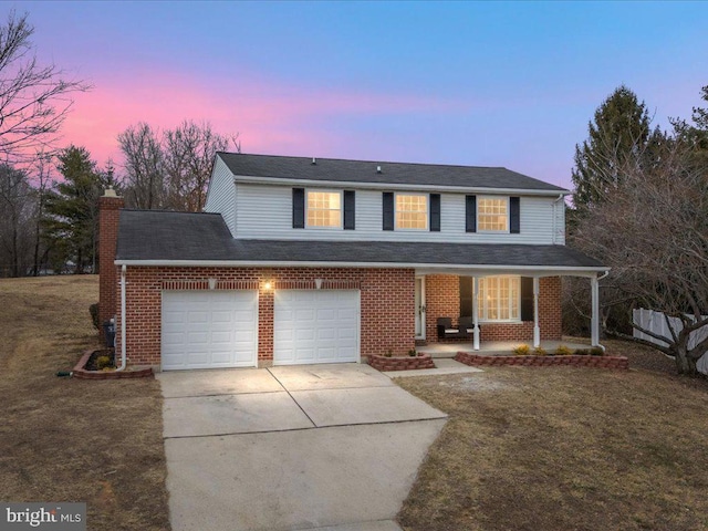 traditional-style home with a porch, a front yard, concrete driveway, and a chimney