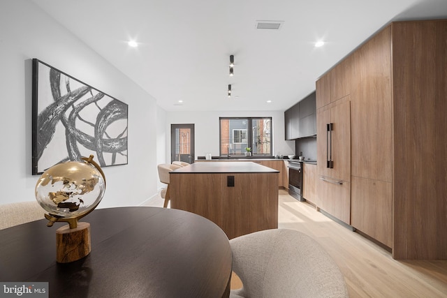 kitchen with sink, stainless steel electric stove, light hardwood / wood-style floors, and a center island