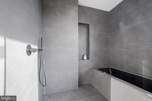 bathroom with tiled shower and tile patterned floors