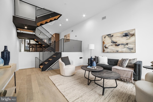 living room featuring a towering ceiling and light hardwood / wood-style floors