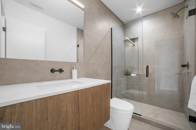 bathroom featuring a shower with door, tile walls, vanity, decorative backsplash, and toilet