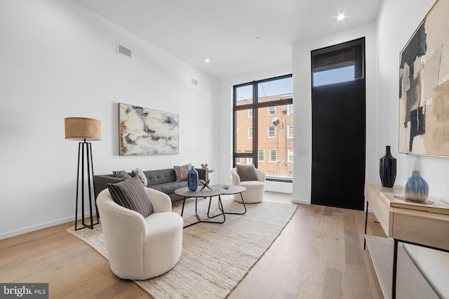 living room with baseboard heating and light hardwood / wood-style flooring