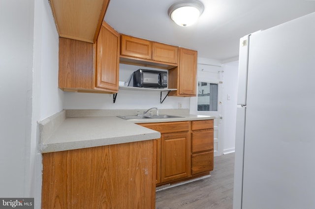 kitchen with white refrigerator, sink, and light hardwood / wood-style flooring