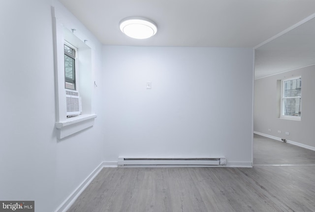 spare room featuring cooling unit, light hardwood / wood-style flooring, and baseboard heating