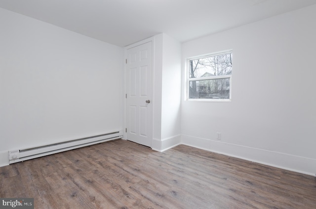 unfurnished room with hardwood / wood-style flooring and baseboard heating