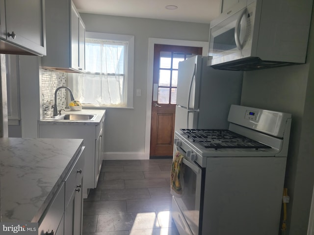 kitchen with white appliances, light stone countertops, and sink