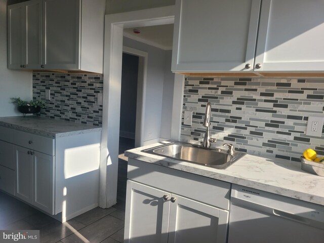 kitchen with stainless steel dishwasher, light tile patterned floors, sink, and backsplash