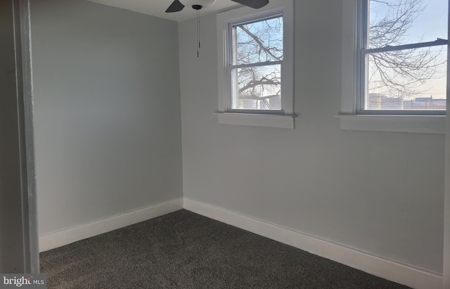 spare room with ceiling fan and dark carpet