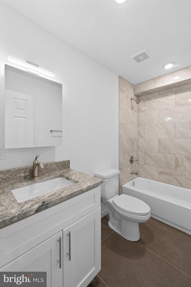 full bathroom with tiled shower / bath combo, vanity, tile patterned flooring, and toilet