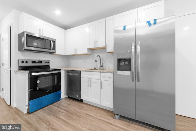 kitchen featuring light wood-type flooring, stainless steel appliances, sink, and white cabinets