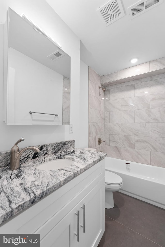 full bathroom with tiled shower / bath, vanity, tile patterned floors, and toilet