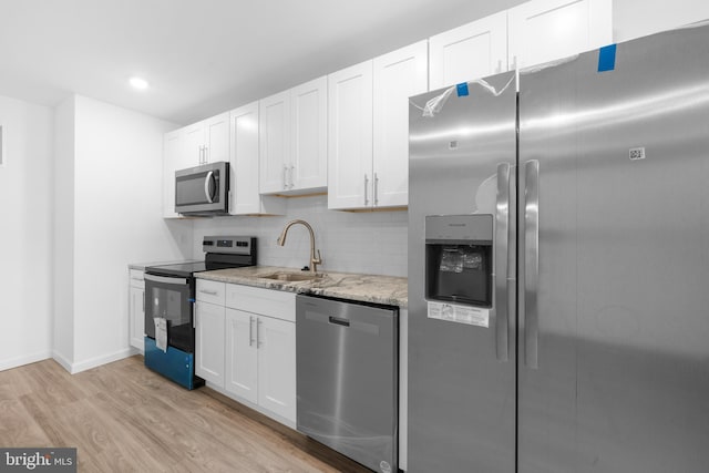 kitchen featuring sink, light hardwood / wood-style flooring, stainless steel appliances, light stone countertops, and white cabinets