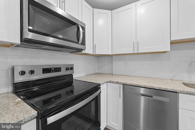 kitchen featuring white cabinetry, light stone counters, decorative backsplash, and stainless steel appliances