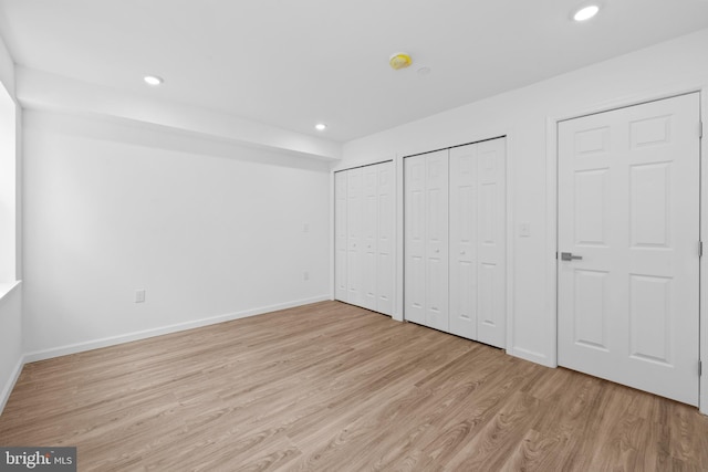 unfurnished bedroom with multiple closets and light hardwood / wood-style flooring