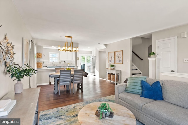 living room featuring an inviting chandelier, sink, and hardwood / wood-style floors