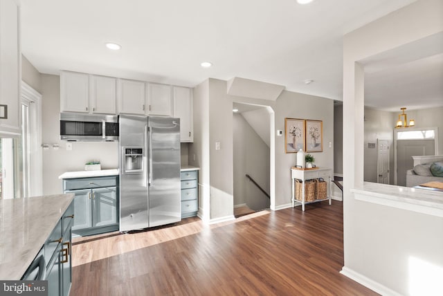 kitchen with stainless steel appliances, white cabinetry, and dark hardwood / wood-style flooring