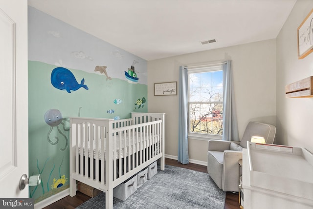 bedroom featuring hardwood / wood-style flooring and a crib