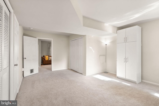 unfurnished bedroom featuring two closets and light colored carpet