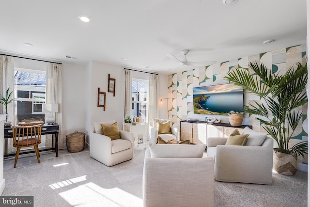 living area with a healthy amount of sunlight, a ceiling fan, visible vents, and light colored carpet