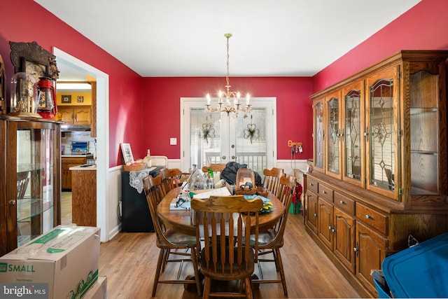 dining room featuring french doors, light wood-style flooring, and an inviting chandelier