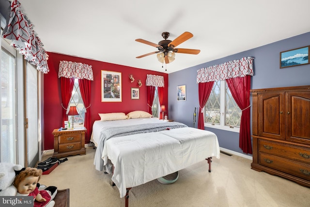 bedroom featuring a ceiling fan, light colored carpet, visible vents, and baseboards