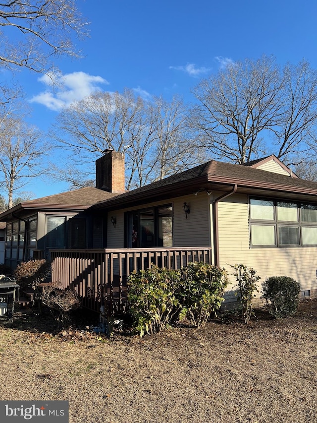 view of side of home featuring roof with shingles and a chimney