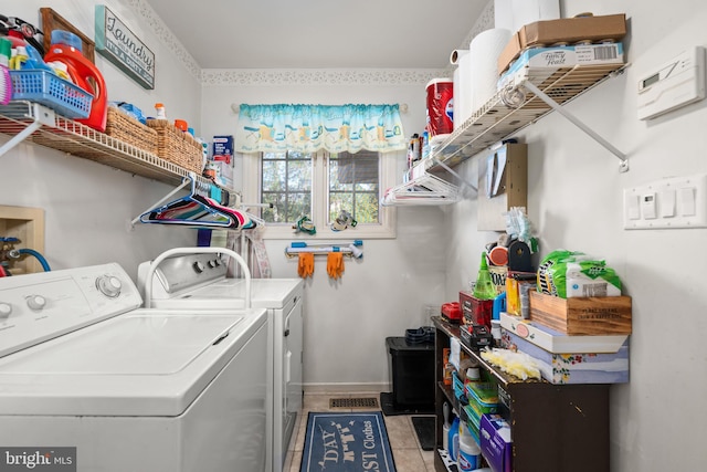 clothes washing area featuring light tile patterned floors, laundry area, baseboards, and washer and dryer