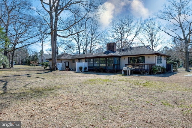 back of property featuring a chimney, central air condition unit, a lawn, a sunroom, and a wooden deck