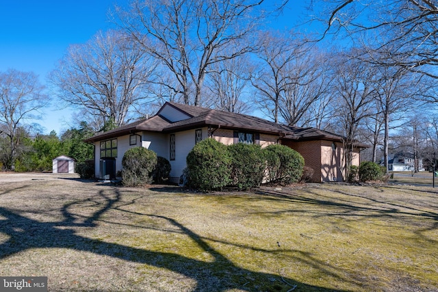 view of side of property with brick siding, an outdoor structure, and a yard