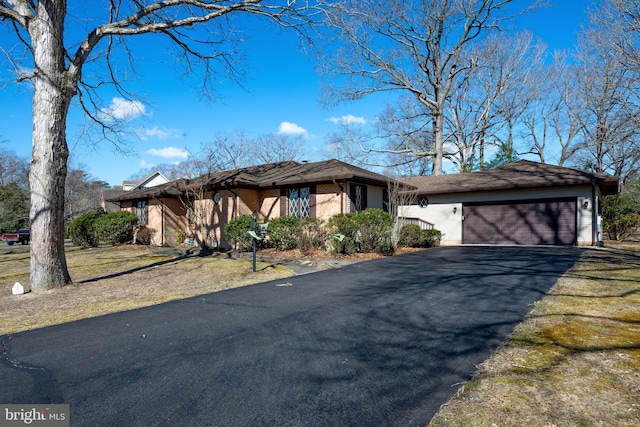 view of front of home featuring an attached garage, aphalt driveway, and brick siding