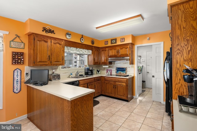 kitchen featuring a peninsula, black appliances, brown cabinetry, and a sink