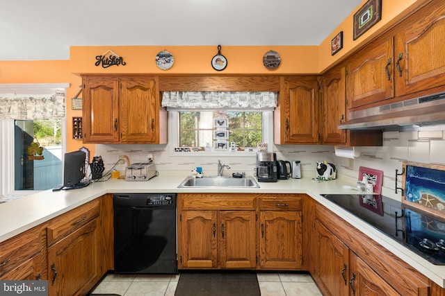 kitchen featuring light countertops, brown cabinetry, a sink, under cabinet range hood, and black appliances