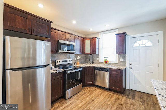 kitchen featuring light stone counters, sink, light wood-type flooring, and appliances with stainless steel finishes