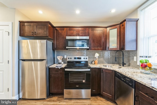 kitchen featuring tasteful backsplash, sink, light hardwood / wood-style floors, and appliances with stainless steel finishes