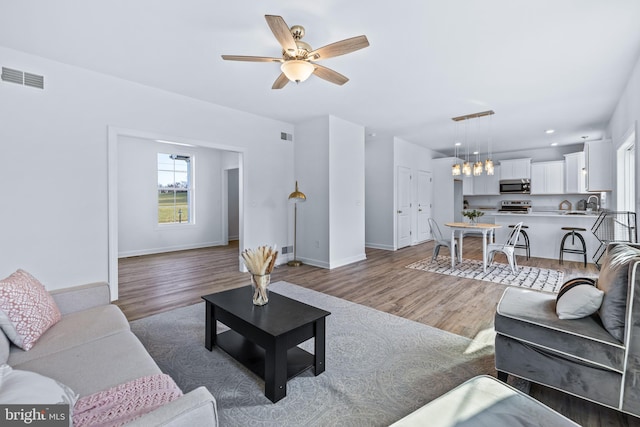 living room with ceiling fan, dark hardwood / wood-style flooring, and sink