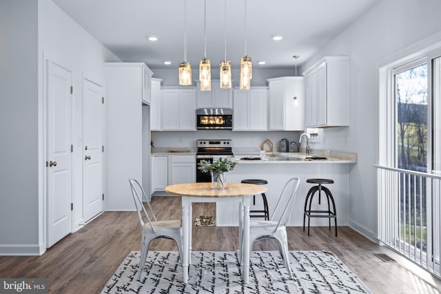 kitchen with white cabinetry, stainless steel range with electric stovetop, a breakfast bar area, and pendant lighting