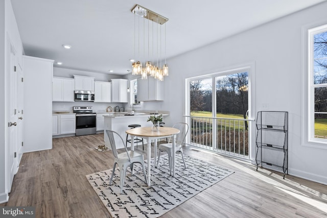 dining space featuring a healthy amount of sunlight, a chandelier, and light wood-type flooring