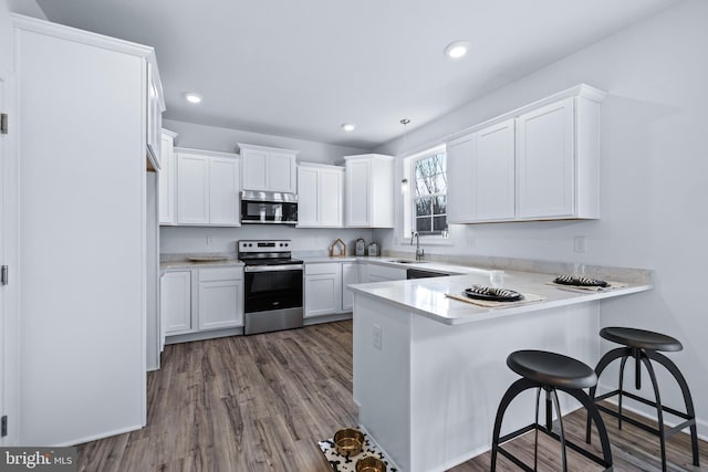 kitchen with sink, white cabinets, a kitchen bar, kitchen peninsula, and stainless steel appliances