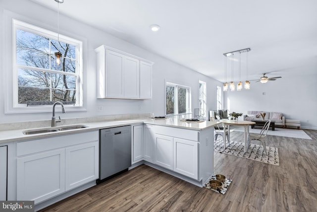 kitchen with sink, white cabinets, hanging light fixtures, stainless steel dishwasher, and kitchen peninsula