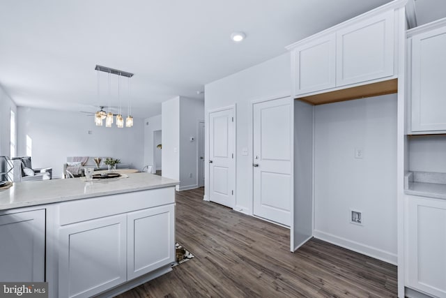 kitchen with pendant lighting, dark wood-type flooring, ceiling fan, light stone counters, and white cabinets