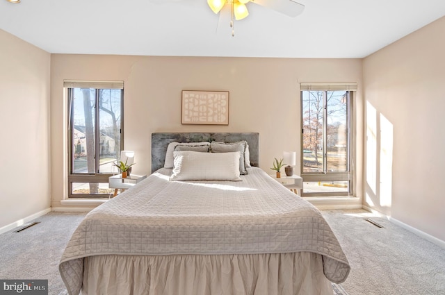 carpeted bedroom featuring multiple windows and ceiling fan