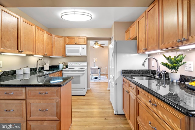 kitchen featuring white appliances, dark stone counters, sink, and light hardwood / wood-style flooring