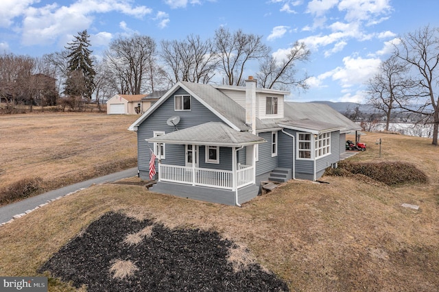 view of front of home with a porch, a garage, an outdoor structure, and a front lawn